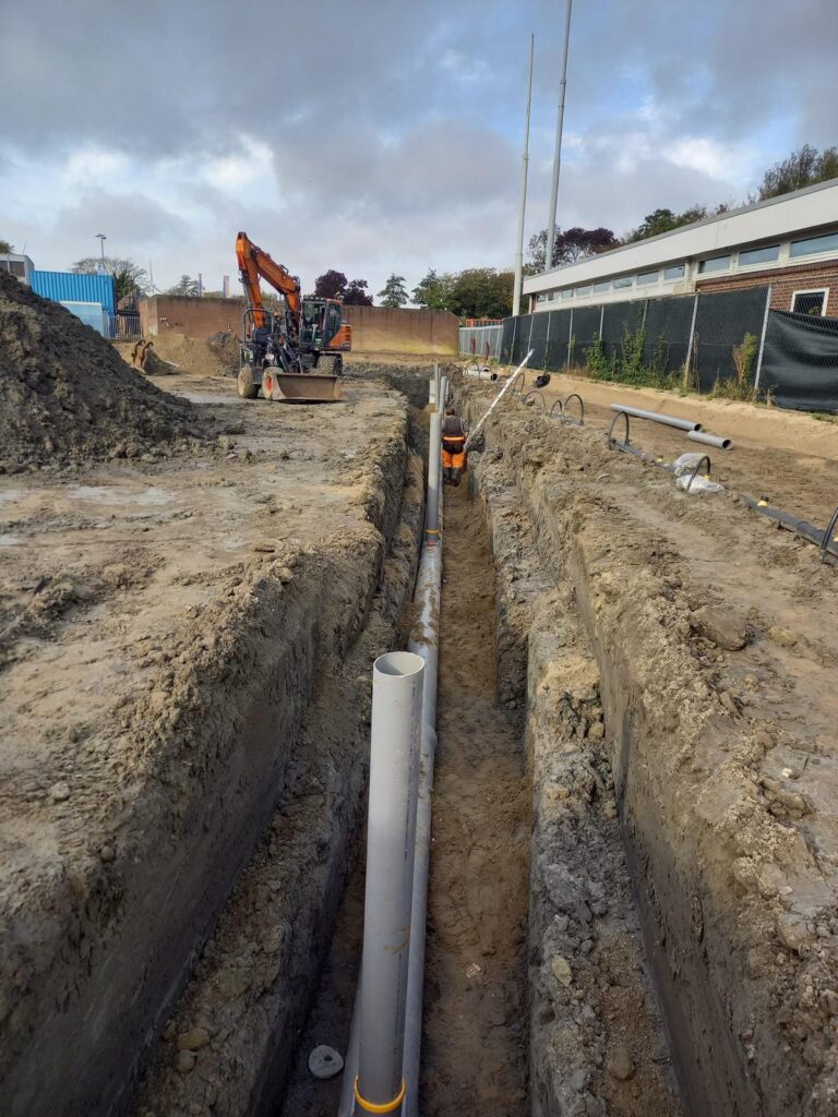 Sleuf met rioolstreng en kraan op de projectlocatie