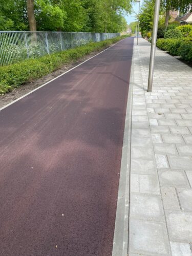 Rood fietspad met strakke band en aansluitende trottoirbestrating