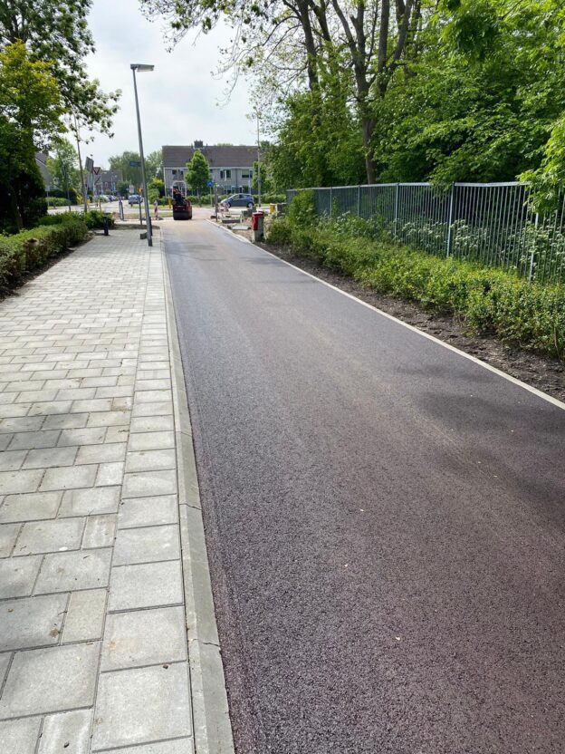 Nieuwe asfaltdeklaag aangebracht met de wals nog op het werk