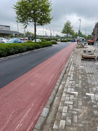 Afgewerkt rood fietspad met nieuwe rijbaan en bestrate berm