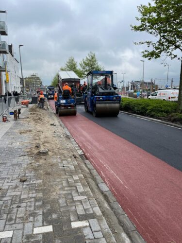 Twee walsen verdichten het rode fietspad naast de zwarte rijbaan