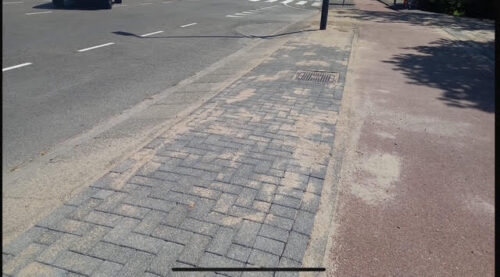 Parkeerstrook in betonstraatstenen met kolk langs de rijbaan