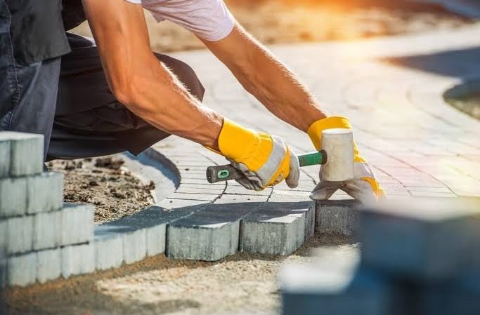 Stratenmaker legt betonstraatstenen aan met een rubberen hamer